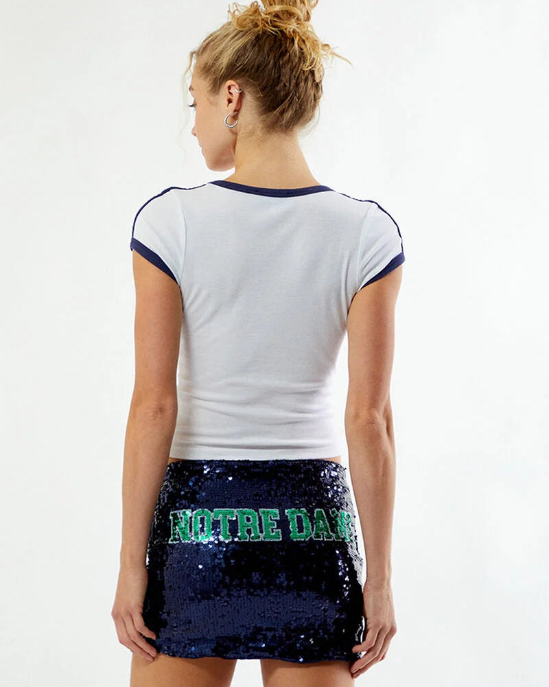 Model wearing a white fitted tee with a navy blue Notre Dame sequin mini skirt on a white background