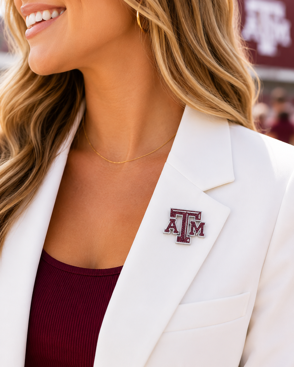 Woman wearing a white blazer and maroon top featuring a Texas A&M crystal logo pin with maroon rhinestone detailing and silver-tone finish.