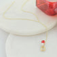 Gold Y necklace with crystal charm, pearl bead and red accent on white background