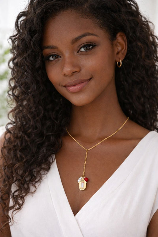 Gold Y necklace with crystal charm, pearl bead and red accent worn on model