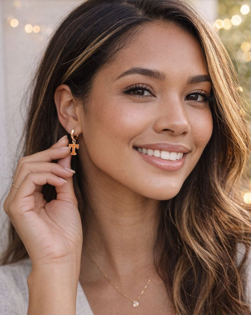 Woman wearing Tennessee Volunteers orange “T” gold hoop earrings