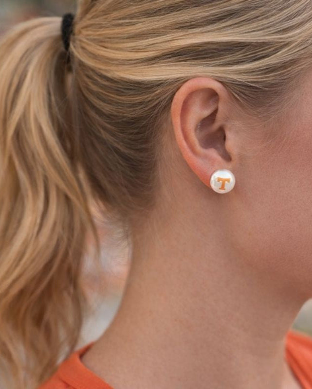 Blonde woman wearing Tennessee Vols pearl stud earrings with orange Power T logo, hair in ponytail